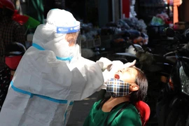 Tiến hành lấy mẫu xét nghiệm cho các tiểu thương kinh doanh, buôn bán tại các chợ trên địa bàn gần vùng thiết lập cách ly. (Ảnh: Xuân Tiến/TTXVN) 