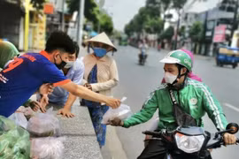Người dân nhận suất ăn miễn phí từ nhân viên nhà hàng Bò tơ Năm Sánh (quận Gò Vấp, Thành phố Hồ Chí Minh). (Ảnh: Hồng Giang/TTXVN) 