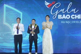 Chủ tịch Hội Nhà báo Việt Nam Thuận Hữu trao giải Ấn tượng cho tác giả Phạm Ngọc Thành (Báo điện tử VnExpress) với bộ ảnh Tìm kiếm nạn nhân lở núi ở Trà Leng. (Ảnh: Hoàng Hiếu/TTXVN) 