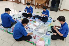 Đoàn viên thanh niên Tỉnh đoàn Tiền Giang làm mũ bảo hộ để tặng các điểm cách ly và các chốt kiểm dịch. (Ảnh: Hữu Chí/TTXVN)