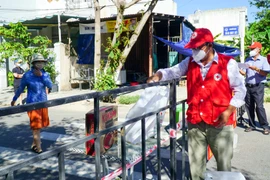 Nhân viên Hội Chữ thập Đỏ thành phố Đà Nẵng đặt túi hàng gia đình ở điểm quy định để người dân trong khu phong tỏa đến nhận, đảm bảo công tác phòng, chống dịch. (Ảnh: TTXVN phát)