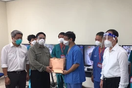 Thủ tướng Phạm Minh Chính tặng quà đội ngũ bác sỹ đang tham gia điều trị bệnh nhân COVID-19 tại bệnh viện dã chiến Hồi sức tích cực ở Bệnh viện quốc tế Becamex tỉnh Bình Dương. (Ảnh: TTXVN) 