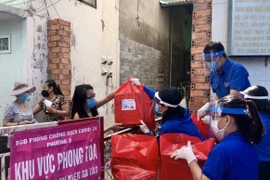 Đoàn viên thanh niên Thành phố Hồ Chí Minh cung cấp nhu yếu phẩm cho những hộ dân thuộc khu vực phong toả tại phường 3, Quận 11. (Ảnh: Hồng Giang/TTXVN) 