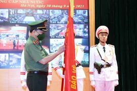 Đại tướng Tô Lâm, Ủy viên Bộ Chính trị, Bộ trưởng Bộ Công an thừa ủy quyền của Chủ tịch nước gắn Huân chương Quân công hạng Nhì lên cờ truyền thống của Cục cảnh sát Phòng cháy chữa cháy và cứu nạn cứu hộ. (Ảnh: Phạm Kiên/TTXVN) 