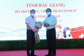 Bí thư tỉnh ủy Long An Nguyễn Văn Được tặng hoa Thạc sỹ Đặng Văn Hòa, Trưởng đoàn Y tế tỉnh Bắc Giang. (Ảnh: Thanh Bình/TTXVN)
