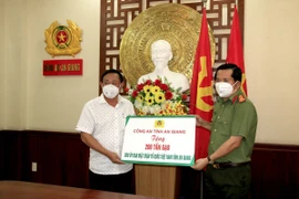 Đại tá Đinh Văn Nơi, Giám đốc Công an tỉnh An Giang (phải) trao biểu trưng tặng 200 tấn gạo cho các bếp ăn tại các khu cách ly tập trung phục vụ người dân từ các tỉnh về quê tự phát. (Ảnh: TTXVN phát)