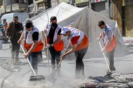 Các tình nguyện viên dọn dẹp đống đổ nát của các tòa nhà bị sập sau loạt không kích của Israel xuống Dải Gaza. (Ảnh: THX/TTXVN) 