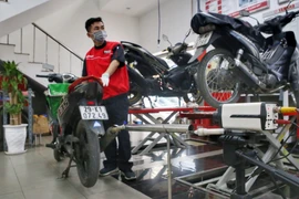 Các nhân viên kiểm tra khí thải xe máy. (Ảnh: Tuấn Đức/TTXVN) 
