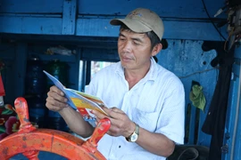 Ngư dân Biện Khắc Linh, thuyền trưởng tàu cá PY 950253, thị xã Đông Hòa đọc thông tin từ sổ tay hướng dẫn bầu cử. (Ảnh: Phạm Cường/TTXVN)