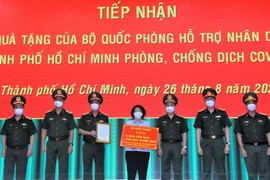 Bà Tô Thị Bích Châu, Chủ tịch Ủy ban Mặt trận Tổ quốc Việt Nam Thành phố Hồ Chí Minh tiếp nhận bảng tượng trưng quà tặng của Bộ Quốc phòng từ Trung tướng Ngô Minh Tiến. (Ảnh: TTXVN phát)