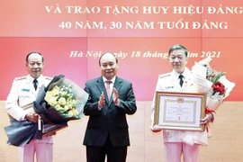 Chủ tịch nước Nguyễn Xuân Phúc trao tặng huy hiệu 40 năm tuổi Đảng cho Đại tướng Tô Lâm, Ủy viên Bộ Chính trị, Bộ trưởng Bộ Công an và Thượng tướng Lê Quý Vương, nguyên Ủy viên Trung ương Đảng, nguyên Thứ trưởng Bộ Công an. (Ảnh: Thống Nhất/TTXVN) 