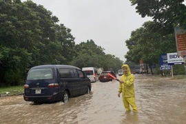 Điều tiết giao thông tại đoạn đường bị ngập úng. (Ảnh: Mạnh Khánh/TTXVN)