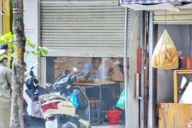 Một quán ăn cố tình mở cửa cho khách ăn sáng trong nhà bị lực lượng chức năng nhắc nhở. (Ảnh: Tuấn Đức/TTXVN) 