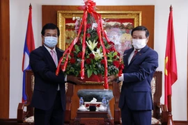 Phó Trưởng Ban Đối ngoại Trung ương Đảng Nhân dân Cách mạng Lào Somphone Sichaleun (trái) trao hoa cho Đại sứ Nguyễn Bá Hùng, chúc mừng 76 năm Quốc khánh Việt Nam. (Ảnh: Phạm Kiên/TTXVN)