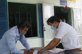 Cán bộ Lao động, Thương binh và Xã hội xã Bình Quới, huyện Châu Thành đến từng nhà trao tiền hỗ trợ cho lao động tự do tạm nghỉ việc do dịch COVID-19. (Ảnh: Đức Hạnh/TTXVN)