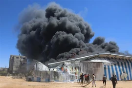 Lính cứu hỏa nỗ lực dập lửa căn nhà bị trúng oanh kích của máy bay Israel tại thành phố Rafah, Dải Gaza. (Ảnh: THX/TTXVN) 