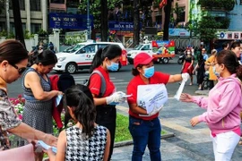 Nhân viên Sở Du lịch Thành phố Hồ Chí Minh phát khẩu trang miễn phí cho khách du lịch. (Ảnh: Đinh Hằng/TTXVN) 