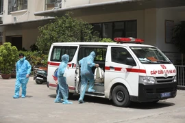 Đưa đi cách ly 2 trường hợp F1 liên quan đến bệnh nhân COVID-19 tại chung cư Thanh Xuân Building. (Ảnh: Minh Quyết/TTXVN) 