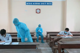 Hai thí sinh trong khu vực phong tỏa ở Phú Yên được bố trí phòng thi riêng, cán bộ coi thi mặc đồ bảo hộ. (Ảnh: Xuân Triệu/TTXVN) 