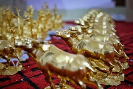 Gia đình nghệ nhân Nguyễn Anh Chung thếp vàng lên tượng trâu vàng cho khách hàng. (Ảnh: Danh Lam/TTXVN)