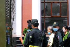 Dẫn giải bị cáo Trịnh Thị Hồng Hoa (áo trắng) sau khi phiên tòa hoãn. (Ảnh: Thành Chung/TTXVN)