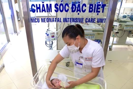 Nữ điều dưỡng Bệnh viện Trung ương Huế tận tình chăm sóc con của một sản phụ mắc COVID-19. (Ảnh: TTXVN phát)