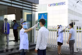 Công nhân được kiểm tra thân nhiệt trước khi vào công ty. (Ảnh: Hoàng Hùng/TTXVN)