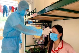 Đo thân nhiệt cho người dân trong khu cách ly. (Ảnh: TTXVN phát)