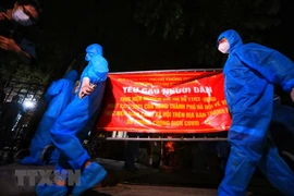 Lực lượng tình nguyện viên gỡ bỏ rào chắn tại ngõ 328, 330 đường Nguyễn Trãi. (Ảnh: Tuấn Anh/TTXVN) 