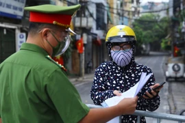 Công an kiểm tra giấy tờ đi đường của người dân phường Chương Dương khu vực được phép ra ngoài khi cần thiết (ảnh chụp sáng 17/8 tại cửa khẩu Cầu Đất). (Ảnh: Hoàng Hiếu/TTXVN) 