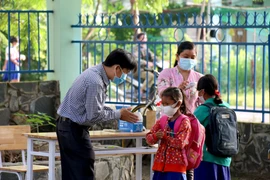 Thầy cô giáo trường Tiểu học và Trung học cơ sở Đông Tiến (xã Đông Tiến), tỉnh Bình Thuận hướng dẫn các em sát khuẩn tay trước khi vào lớp. (Ảnh: Nguyễn Thanh/TTXVN) 