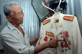 Đại tá Bành Văn Đởm bên những huân, huy chương được tặng thưởng. (Ảnh: TTXVN phát)