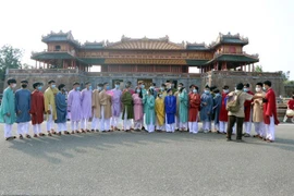 Du khách mặc áo dài truyền thống, đeo khẩu trang phòng dịch chụp ảnh trước cửa Ngọ Môn, Kinh thành Huế. (Ảnh: Đỗ Trưởng/TTXVN)