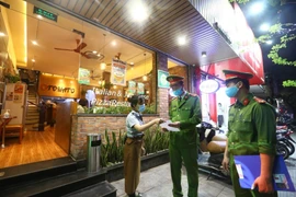 Công an phường Nguyễn Du (Hà Nội) tuyên truyền, nhắc nhở các cửa hàng đóng cửa theo quy định phòng chống dịch COVID-19 (26/3/2020). (Ảnh: Minh Quyết/TTXVN) 