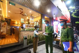 Công an phường Nguyễn Du (Hà Nội) tuyên truyền, nhắc nhở các cửa hàng đóng cửa theo quy định phòng chống dịch COVID-19 (26/3/2020). (Ảnh: Minh Quyết/TTXVN) 