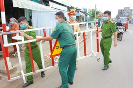 Lực lượng chức năng thực hiện dỡ bỏ phong tỏa cho 20 hộ dân tại khu phố 2, phường Xuân Thanh. (Ảnh: Lê Xuân/TTXVN) 