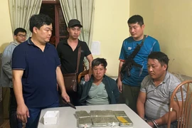 Hai đối tượng bị bắt giữ và tang vật. (Ảnh: TTXVN phát)