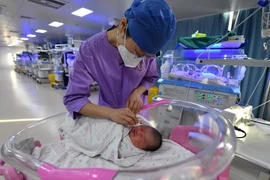 Y tá chăm sóc một đứa trẻ sơ sinh ở bệnh viện nhi tại tỉnh An Huy, Trung Quốc ngày 17/1/2024. (Ảnh: AP)
