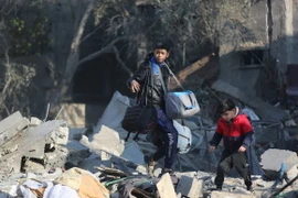 Người dân nhặt nhạnh đồ đạc còn sót lại trong đống đổ nát sau vụ không kích của Israel xuống trại tị nạn Al-Maghazi ở Dải Gaza ngày 31/12/2023. (Ảnh: THX/TTXVN)