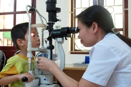 Cán bộ y tế khám mắt cho bệnh nhân. (Ảnh: TTXVN)