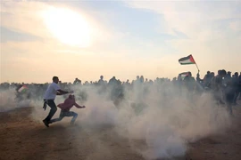 Người biểu tình Palestine chạy trốn đạn hơi cay trong cuộc xung đột với binh sỹ Israel tại thành phố biên giới Khan Yunis, phía nam Dải Gaza ngày 9/11/2018. (Ảnh: AFP/ TTXVN)