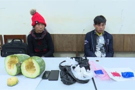 Hai đối tượng Mùa A Pàng (bên phải, sinh năm 2000) và Mùa Thị Mang (sinh năm 1984), cùng trú tại xã Nặm Khắt, huyện Mù Căng Chải, tỉnh Yên Bái cùng tang vật tại cơ quan công an. (Ảnh: TTXVN phát)