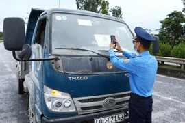 Lực lượng chức năng quét mã QR của phương tiện tham gia giao thông tại chốt kiểm soát dịch ngã 3 Cầu Giẽ, huyện Phú Xuyên hướng từ Hà Nam về Hà Nội trên tuyến Quốc lộ 1A. (Ảnh: Phạm Kiên/TTXVN)
