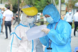 Nhân viên y tế kiểm tra danh sách người xét nghiệm. (Ảnh: Văn Dũng/TTXVN)