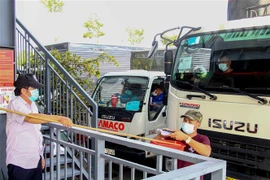 Tài xế trình giấy tờ tại chốt kiểm soát trong Bến xe trung tâm thành phố Cần Thơ để được vào thành phố giao nhận hàng hóa. (Ảnh: Thanh Liêm/TTXVN)