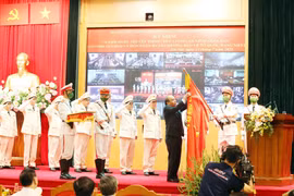 Chủ tịch nước Nguyễn Xuân Phúc gắn Huân chương Bảo vệ Tổ quốc hạng Nhất lên lá cờ truyền thống của lực lượng an ninh nhân dân. (Ảnh: Phạm Kiên/TTXVN)