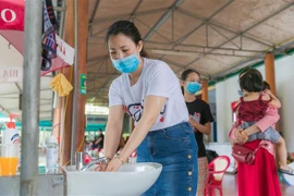 Du khách được hướng dẫn rửa tay sát khuẩn, đeo khẩu trang khi đến các điểm dịch vụ tại thị xã Cửa Lò. (Ảnh: Bích Huệ/TTXVN)