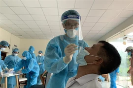 Nhân viên y tế lấy mẫu xét nghiệm COVID-19 cho người dân. (Ảnh: TTXVN phát)