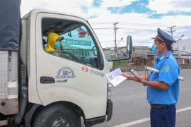 Lực lượng Thanh tra giao thông kiểm tra giấy tờ của một xe tải chờ hàng hóa vào thành phố Cần Thơ. (Ảnh: Thanh Liêm/TTXVN)
