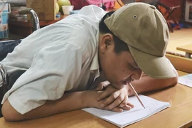 Anh Phùng Văn Trường viết chữ bằng miệng. (Ảnh: PV/Vietnam+)